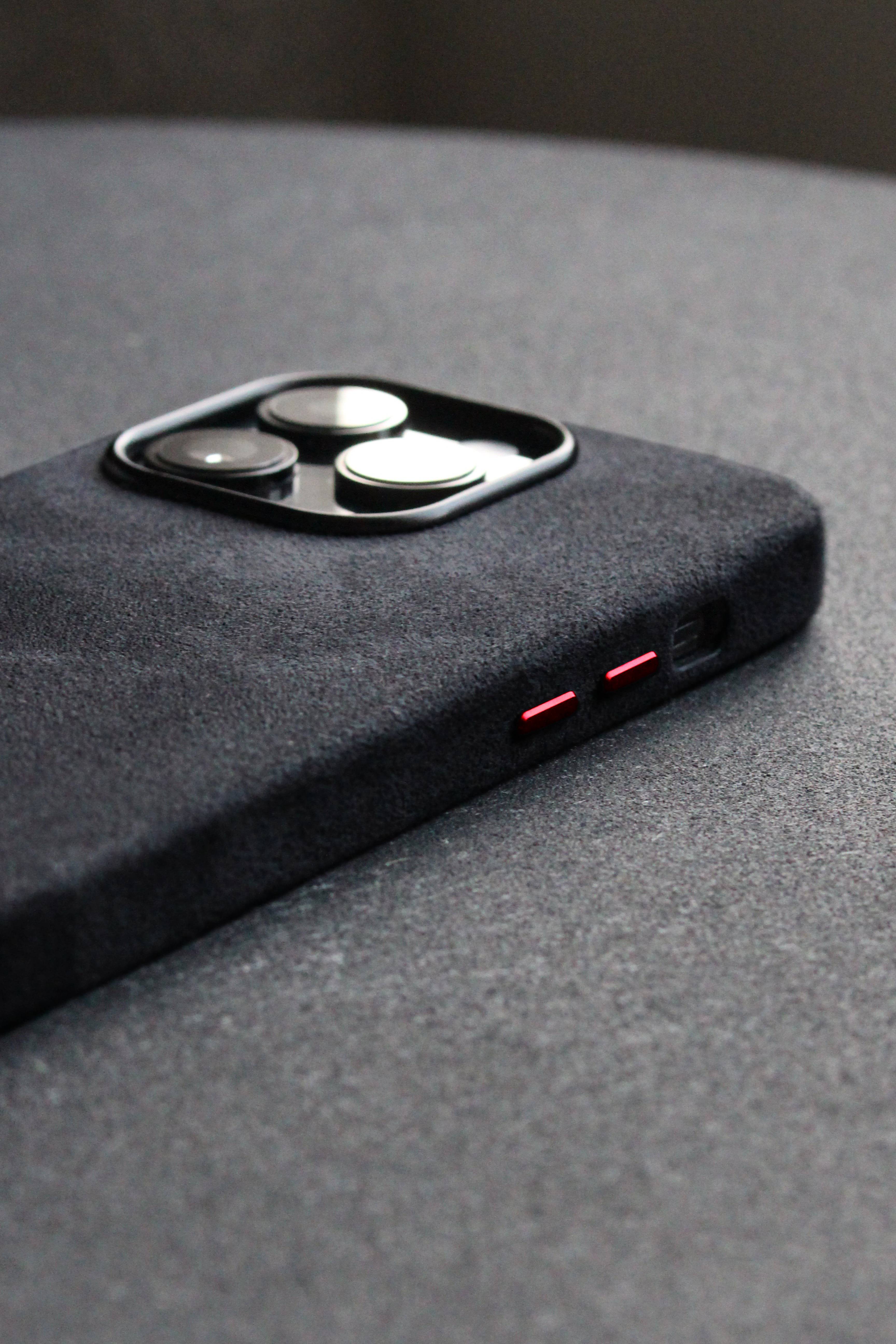 Close-up of a black phone case with red accents on a gray surface