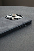 Close-up of a gray phone case with camera lens protector on a gray surface