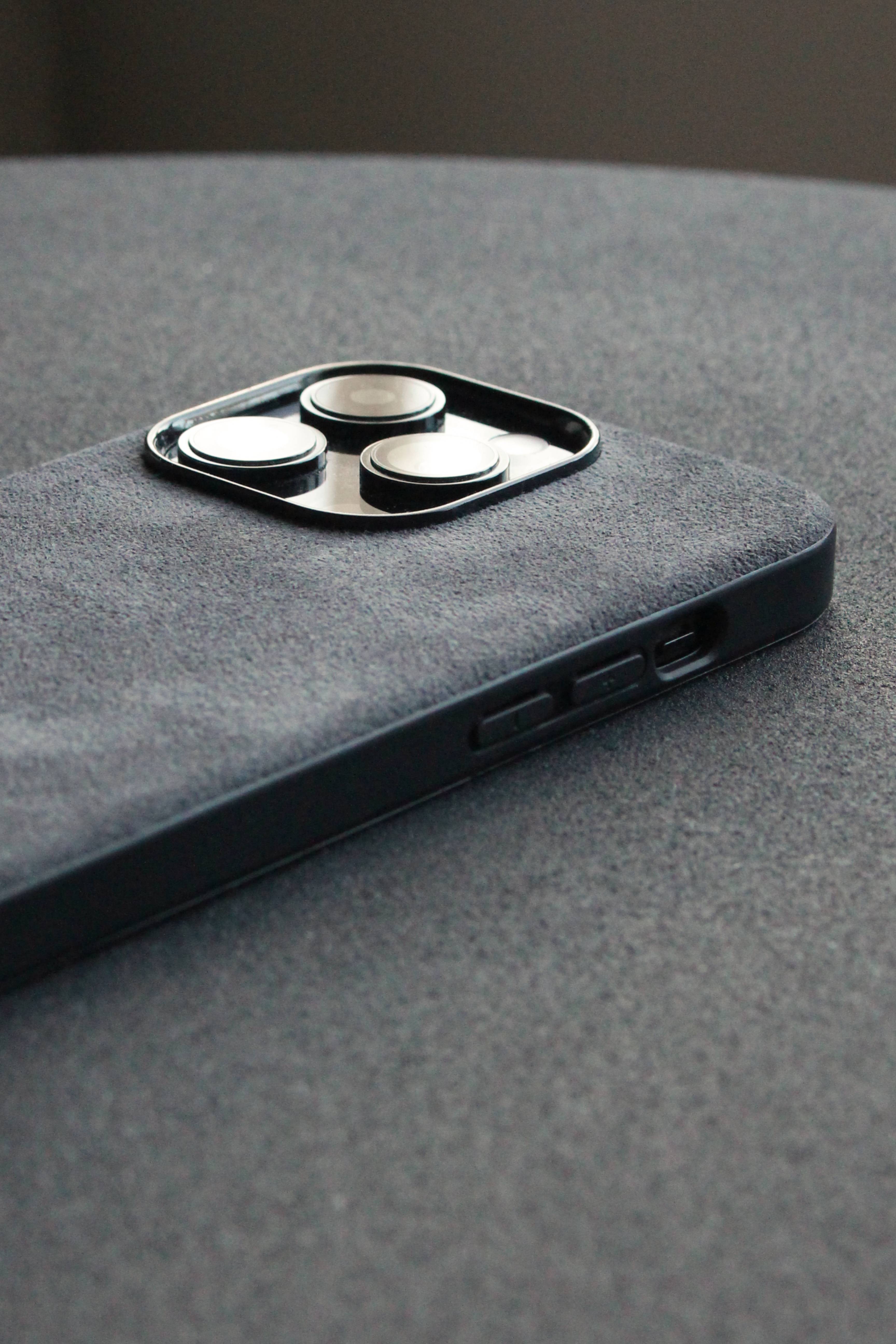 Close-up of a gray phone case with camera lens protector on a gray surface